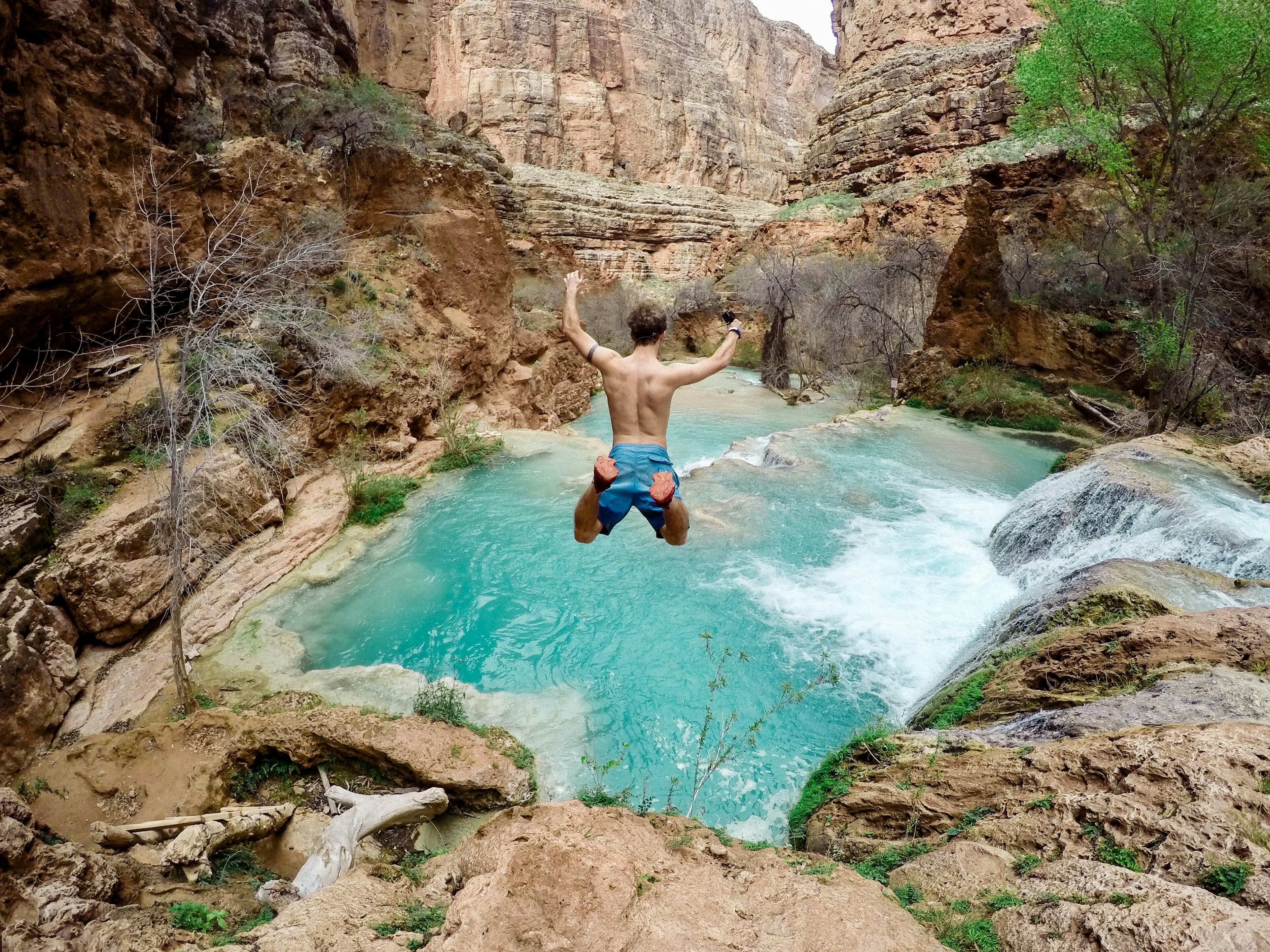 time lapse photography of man jumping on waterfalls